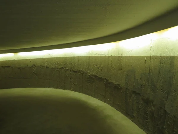 Perspective of a concrete car ramp of a car parking with artificial lights