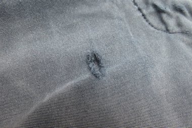 Gri kumaş yüzeyi ile yamalı delik arka plan olarak yararlı