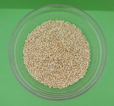 Quinoa (Chenopodium quinoa) bir cam kabın içinde yeşil arka plan üzerinde kabarık.