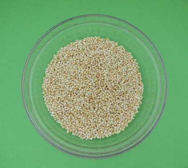 Quinoa (Chenopodium quinoa) bir cam kabın içinde yeşil arka plan üzerinde kabarık.