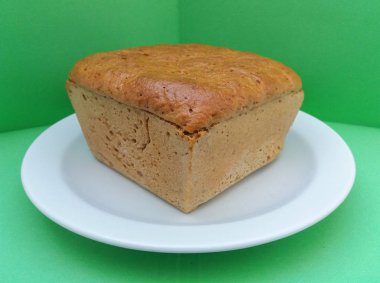 çavdar ekmeği somun yeşil bir arka plan üzerinde beyaz bir tabak içinde