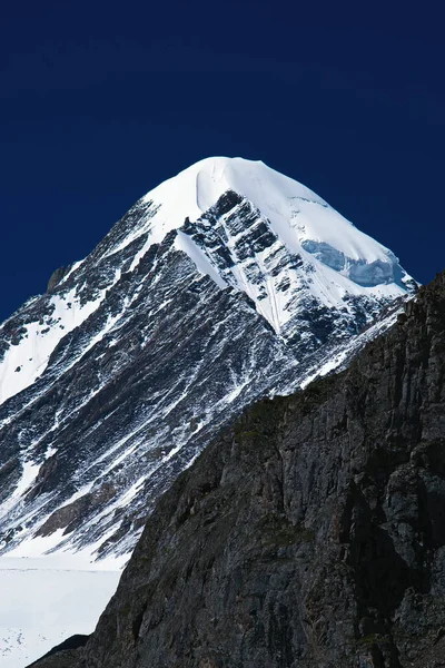 Pico de montanha alta coberta de neve contra — Fotografia de Stock