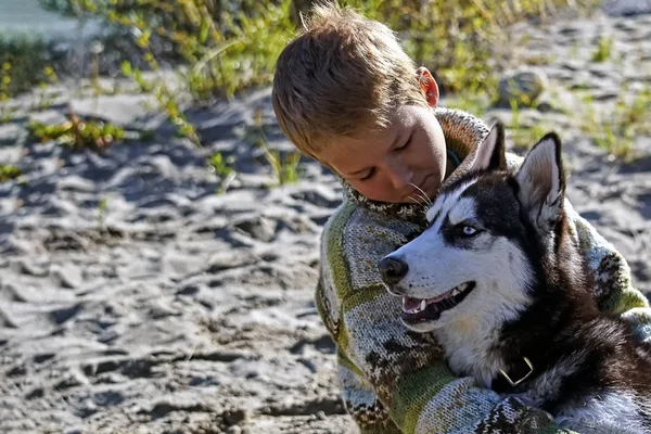 Niño abrazando a un husky siberiano — Foto de Stock