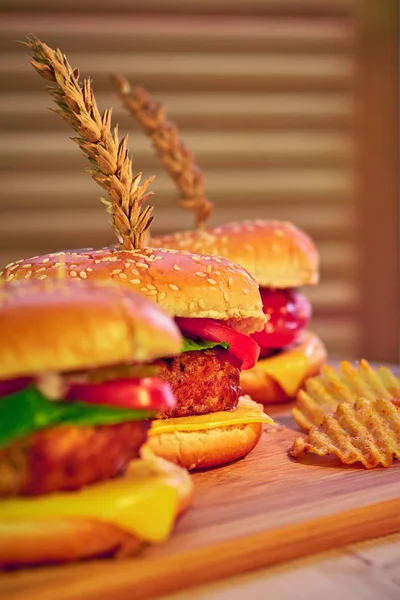 Hambúrgueres de carne grelhada saborosos com alface, tomate, queijo e maionese em mesa de madeira rústica. Gamburgers caseiros, espaço de cópia. Comida rápida. Foco seletivo . — Fotografia de Stock