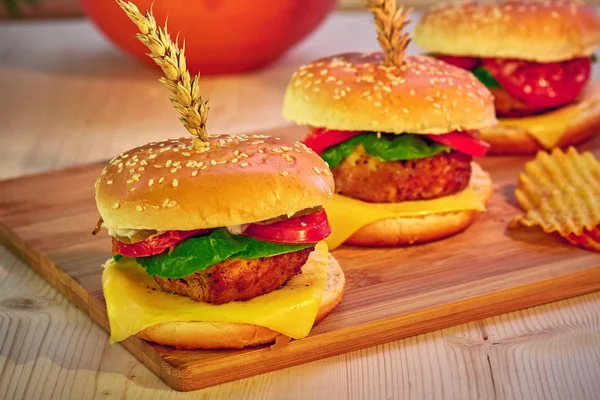 Deliciosas hamburguesas a la brasa con lechuga, tomate, queso y mayonesa sobre tabla rústica de madera. Gamburguesas caseras, espacio para copiar. Comida rápida. Enfoque selectivo . — Foto de Stock