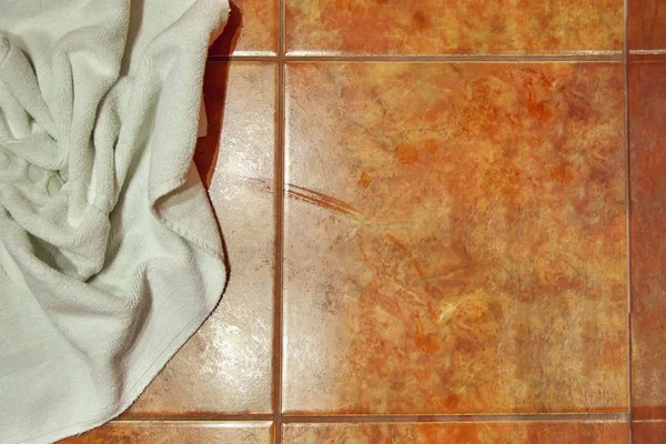 Kopieer ruimte. Natte gevouwen witte handdoek op stenen vloer in de badkamer. Keramische tegels warme kleuren. Voor achtergrond. — Stockfoto