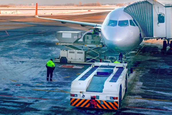 Aviones conectados a una pasarela telescópica de proa o de pasajeros en el delantal del aeropuerto. Se prepara para abordar pasajeros a través de una escalera telescópica . — Foto de Stock