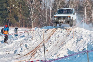 Tomsk, Rusya - 17 Şubat 2018: Kış Otomobil Fuarı, cip - ring yarış engeller, off-road deneme ile. Cip atlama. Yüksek atlama üzerinden sıçrama tahtası beyaz arabaya. Offroad kavramı.