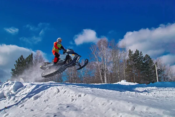 Carreras deportivas motos de nieve. Moto de nieve en salto por encima de pista. Deportista en moto de nieve. Competencia de invierno, día soleado. Copiar espacio . —  Fotos de Stock