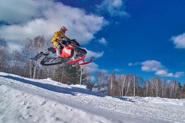 Sport red snowmobile jump. Clear sunny winter day. Concept quick movement. clipart