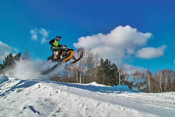 Sport geel sneeuwscooter springen. Zonnige winterdag met blauwe lucht. Concept snelle beweging. — Stockfoto