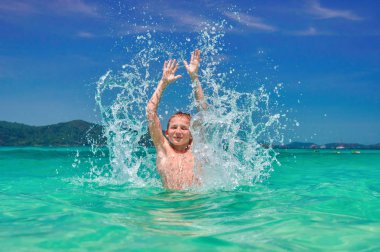 Denizde geçirilen silahlarla sıçramasına çocuk. Eller erkek (10 yaşında) yukarı turkuaz su tropikal deniz deniz manzarası, parlak gökyüzü ve deniz.