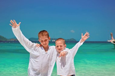 İki mutlu gülümseyen çocuklar (8-12 yaş) sahilde sarılma ve onun ellerini o. çocuklar beyaz burunları giyindin.