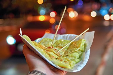 Asya sokak gıda kavramı, fastfood. Tatlı krep muz ve yoğunlaştırılmış süt ile doldurulmuş. Ahşap çubuklar. Gece vakti.