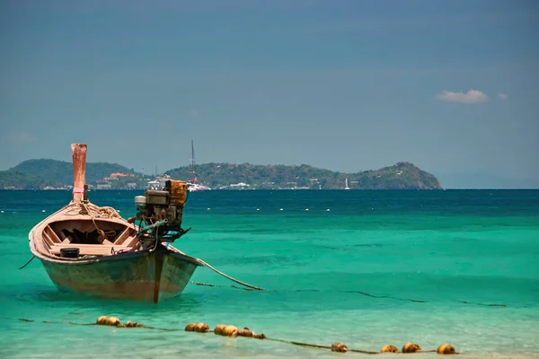 Conceito paraíso tropical. Barco de pesca de madeira nas águas azul-turquesa no fundo das ilhas e céu azul em dia ensolarado . — Fotografia de Stock