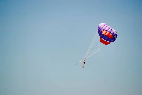 Parasailing. Człowiek leci na spadochron w jasnym błękitnym niebie. Widok z boku. Kopiuj przestrzeń. — Zdjęcie stockowe