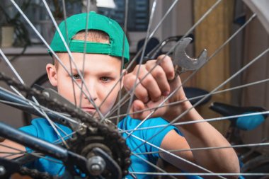 Çocuk yaşında evde bir bisiklet onarımı 10. Bir somun oturma, yaşam tarzı tasarım içinde büyük somun anahtarı ile gevşeterek portre çocuk.