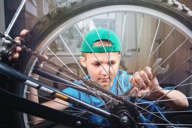 Evde bir bisiklet onarımı çocuk. Bir somun oturma, yaşam tarzı tasarım içinde büyük somun anahtarı ile gevşeterek portre çocuk.