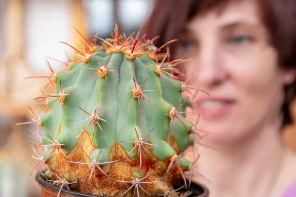 Großer grüner stacheliger Kaktus in Großaufnahme. Gegen das lächelnde Gesicht der schönen Frau — Stockfoto