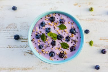 Bir kase tahıl ve taze meyve ile sağlıklı ve lezzetli blueberry smoothie.