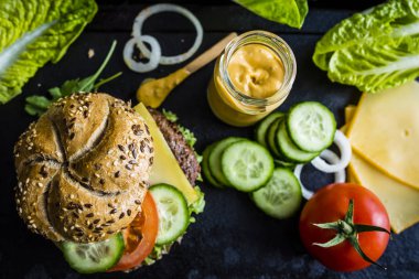Lezzetli ızgara ve sırlı biftek burger marul, peynir ve antika arka plan üzerinde sebze füme.