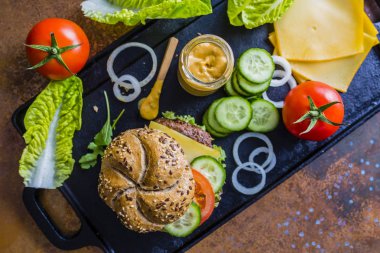 Lezzetli ızgara ve sırlı biftek burger marul, peynir ve antika arka plan üzerinde sebze füme. 