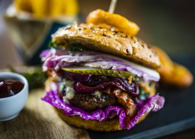 Lezzetli füme ızgara ve sırlı sığır eti burger marul, peynir ve domuz pastırması patates kızartması ile servis.
