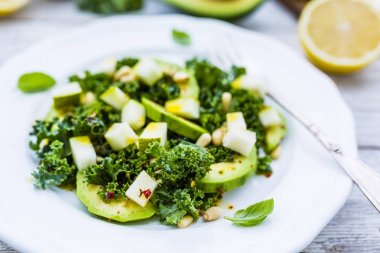Taze lahana yaprakları ve armut ahşap masa üzerinde beyaz bir plaka üzerinde Avokado salatası.