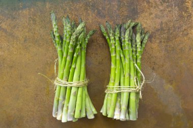 Vintage bir arka plan üzerinde taze ve çiğ yeşil kuşkonmaz demet. 