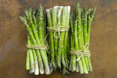 Vintage bir arka plan üzerinde taze ve çiğ yeşil kuşkonmaz demet. 