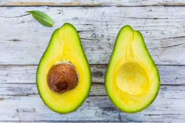 Ahşap bir arka planda olgun avokado yarıları.