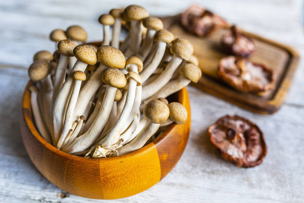 Fresh Shimeji and Shitake mushrooms on a wooden background.