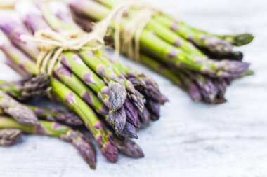 Ahşap arka planda taze ve çiğ kuşkonmaz demetleri. 