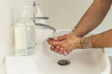 Koronavirüs önleme için dezenfektan jeliyle ellerini yıkayan adam. Koronavirüs yayılmasını engellemek için hijyen..