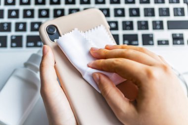 Cep telefonu kılıfının yüzeyini temizliyorum. Coronavirus önleme, koronavirüs yaymayı durdurmak için hijyen..