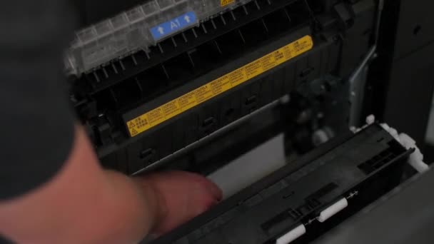 Mann entfernt Papier, das im Drucker im Büro steckt — Stockvideo