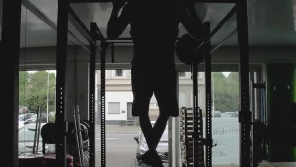 Spor Salonundaki Yatay Çubukta Barfiks Çeken Genç Bir Adamın Silüeti — Stok video