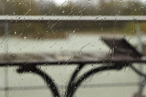 Picături de ploaie pe sticlă cu vedere la masă, scaun și scrumieră — Fotografie, imagine de stoc