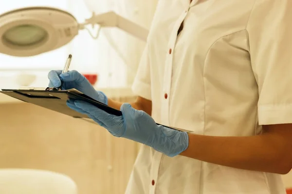 The doctor in a white coat writes the results of the survey.