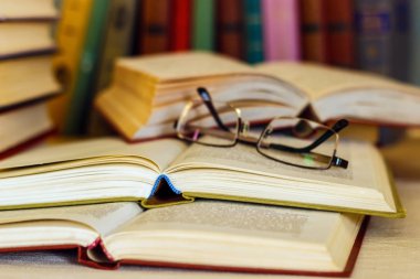 Masanın üzerine birçok kitap ve gözlük vardır.