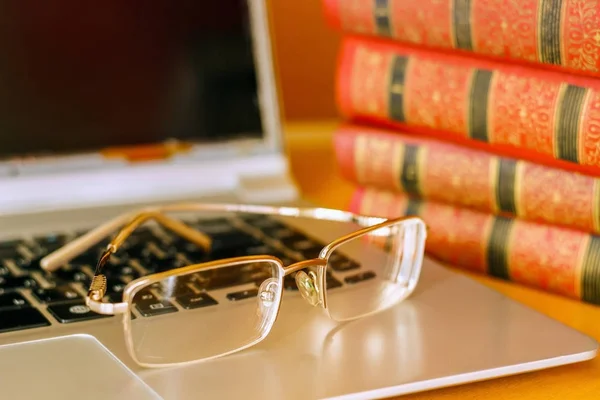 Op de tafel zijn boeken in een rode kaft en een laptop. Stockfoto