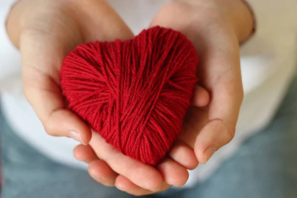 Kırmızı iplik örme için kalpli bir çocuk elele tutuşun. Valent