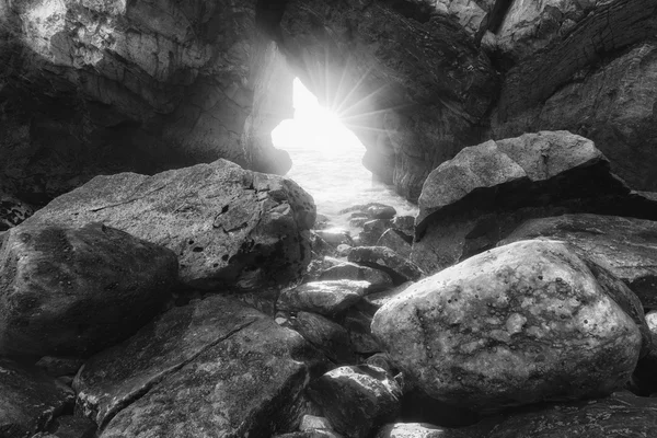 Monochrome photo of sunlight through rock arch — Stock Photo, Image