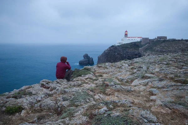 Man sitter på en klippa med utsikt över St. Vincente Lighthouse — Stockfoto
