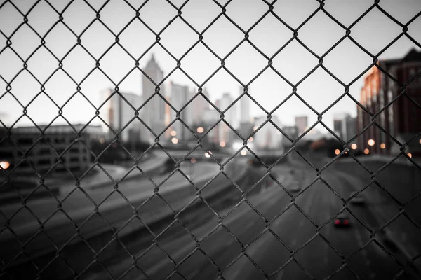 Skyline cidade através da cerca de malha de arame — Fotografia de Stock