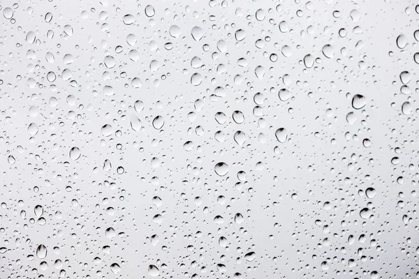 Σταγόνες νερού σε αφηρημένα φόντο λευκό γυαλί — Φωτογραφία Αρχείου