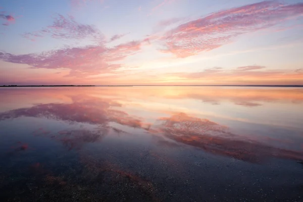 Pôr do sol nublado bonito colorido sobre a superfície da água do oceano — Fotografia de Stock