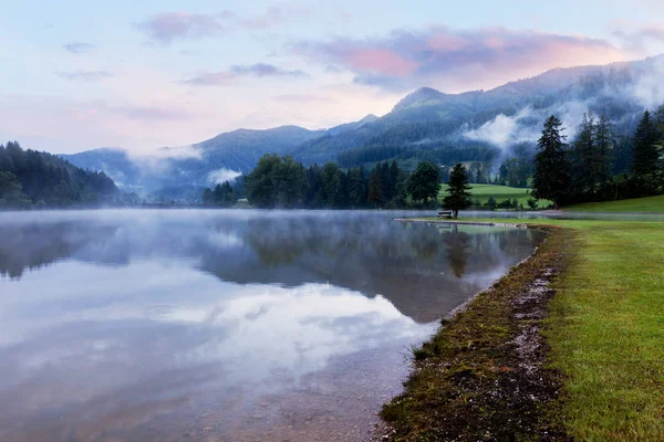 Montaña alpina lago de verano a la salida del sol nublado niebla —  Fotos de Stock