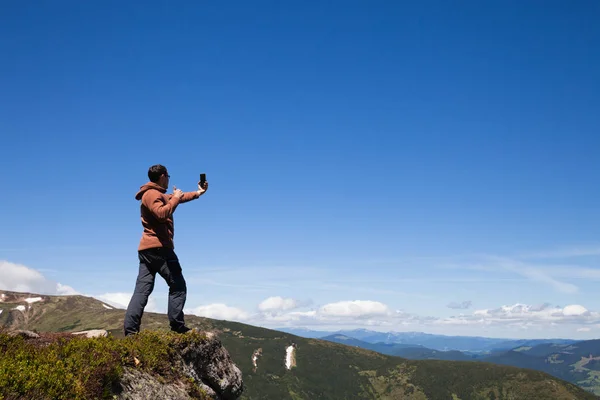 Человек на вершине горы делает селфи по мобильному телефону — стоковое фото