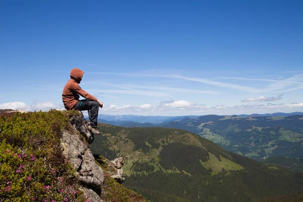 Dağın tepesinde oturan ve ufka bakarak adam — Stok fotoğraf